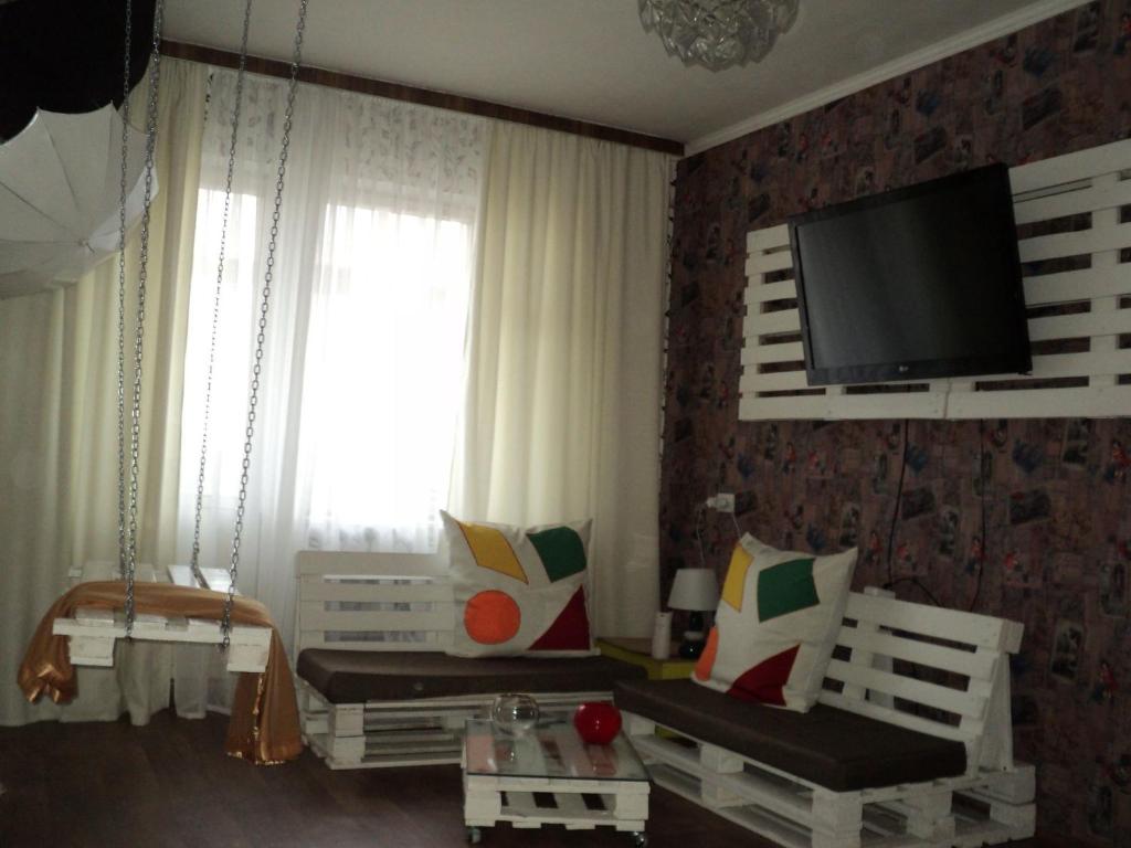 a living room with two white chairs and a flat screen tv at Apartment on Vasylia Stusa St, 10 in Bila Tserkva