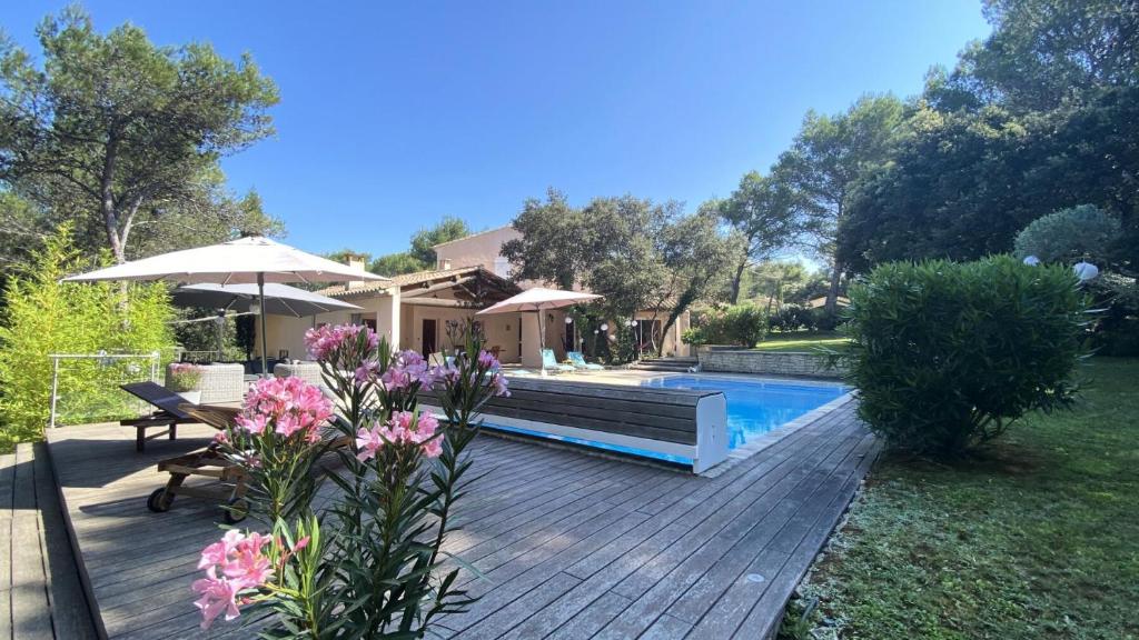 un patio trasero con terraza de madera y piscina en Les Mas et Villas de Pont Royal en Provence - maeva Home - Maison pièces av 064, en Mallemort