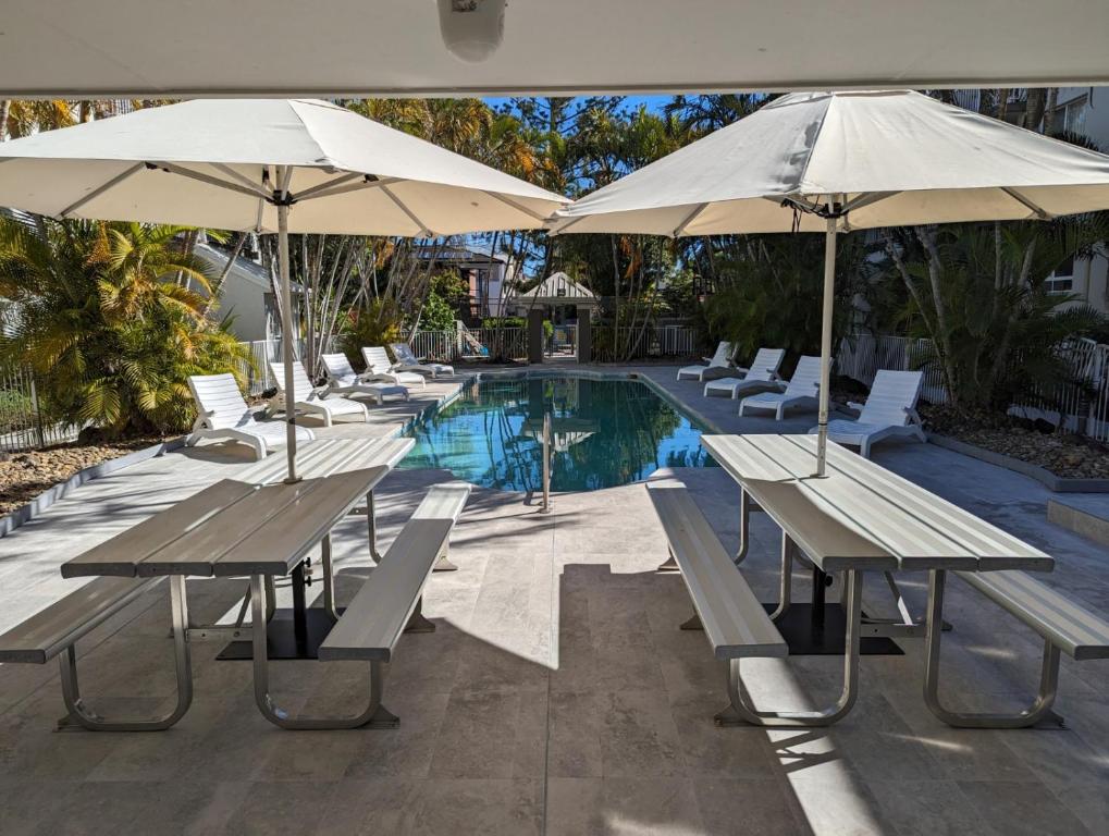 a group of tables and umbrellas next to a pool at Bay Lodge Apartments in Gold Coast