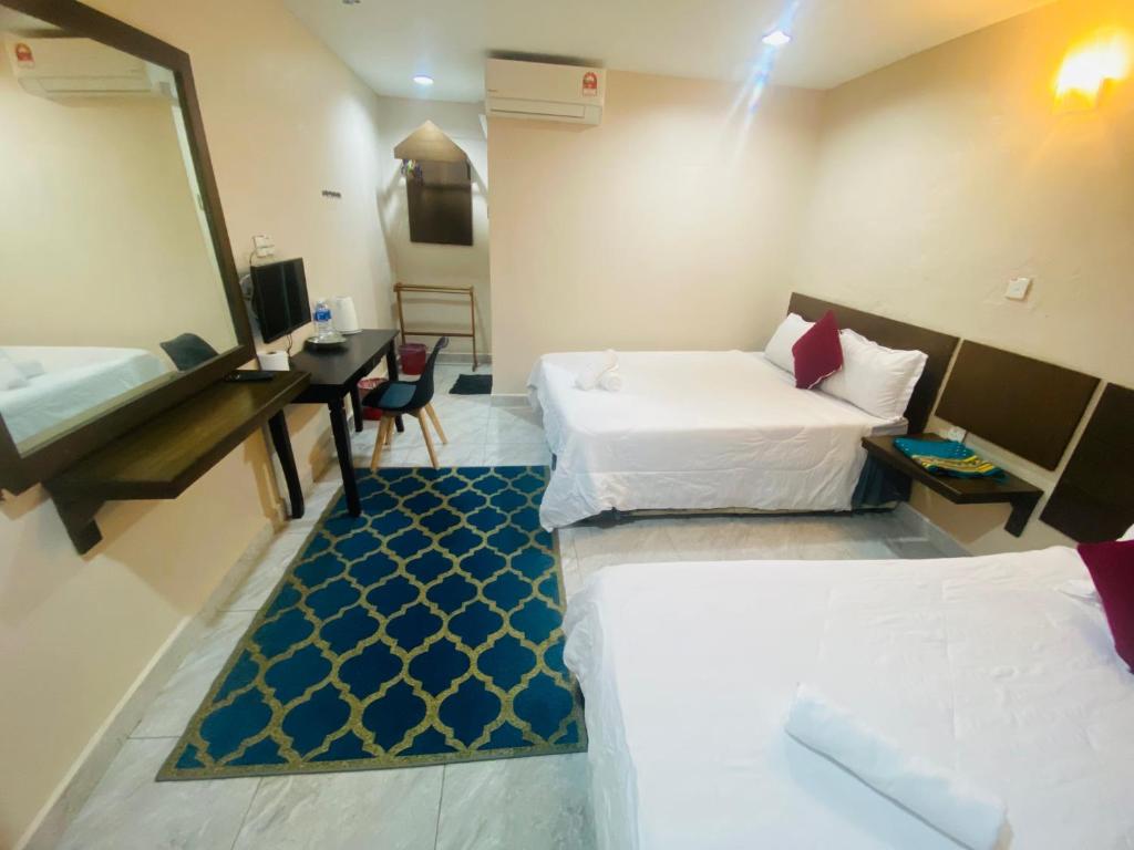 a hotel room with two beds and a desk at Motel Seri Mutiara in Kuah