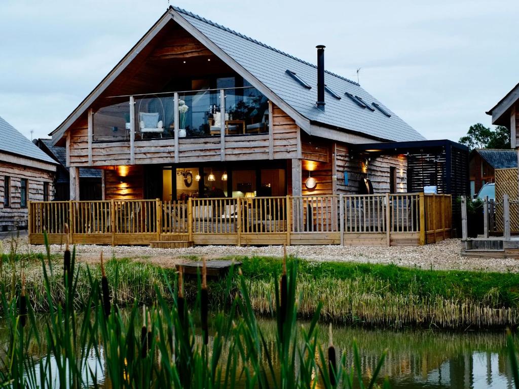a log house with a large deck and a pond at Lake View Lodge in Lincoln