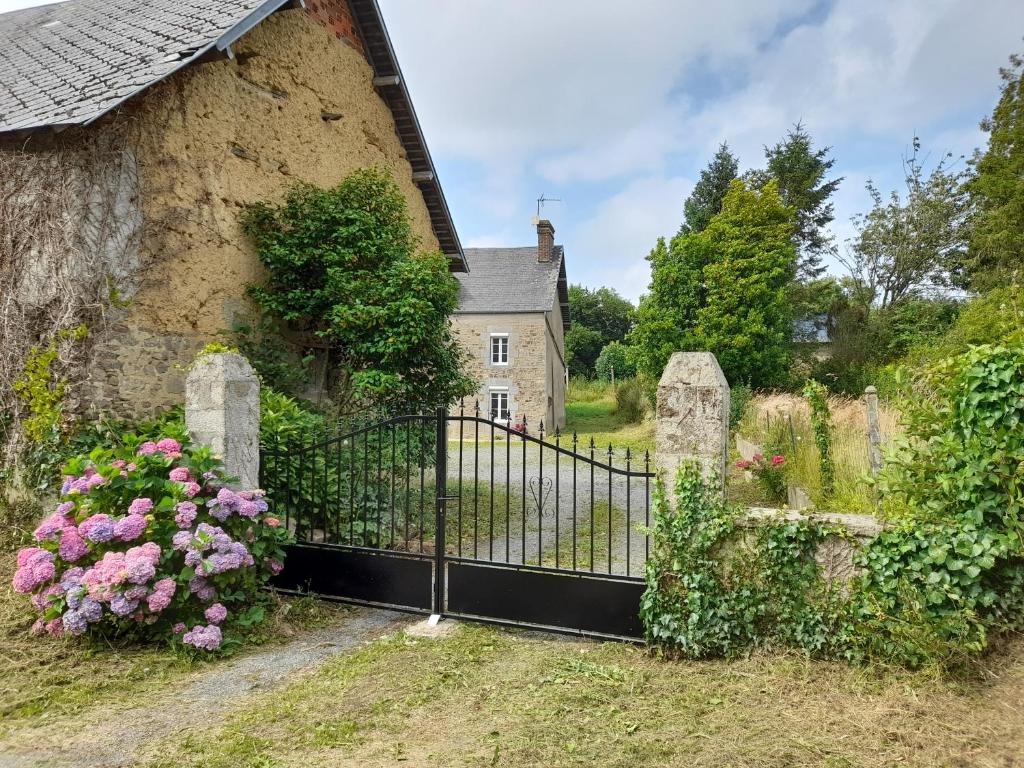 un vecchio cancello di fronte a una casa con dei fiori di Maison en pierre entre terre et mer a Montpinchon