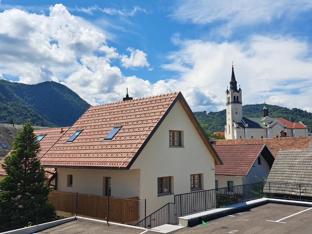 een wit gebouw met een rood dak en een kerk bij Turizem Loka - Hotel Vila Loka in Škofja Loka