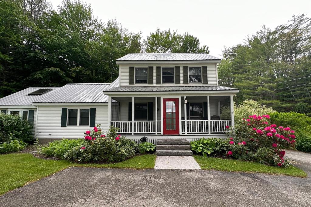 a white house with a red door and some flowers at Cottage at Green Hill in Jackson