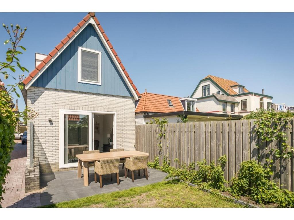 a backyard with a wooden table and a fence at Nice small house in the center of De Cocksdorp on the island Texel in De Cocksdorp