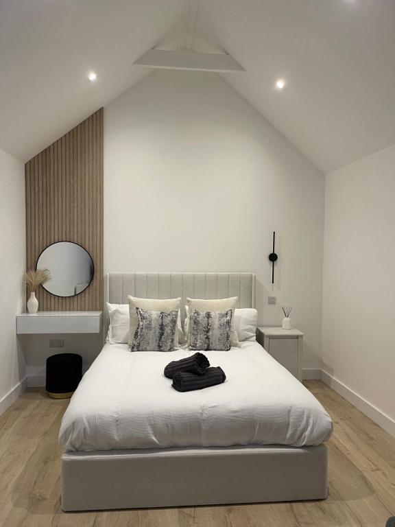 a white bedroom with a large white bed with a mirror at The Lodge Hideaway in Cowes in Gurnard