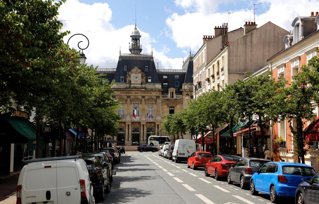 a city street with cars parked in front of a building at Appartement terasse in Saint-Maur-des-Fossés