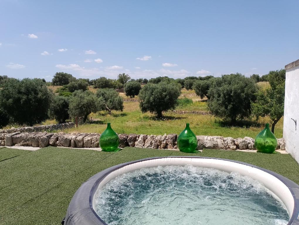 Masseria Le Mesolecchie di Rodio Renato في Crispiano: ثلاث مزهريات زجاجية خضراء جالسة في بركة ماء