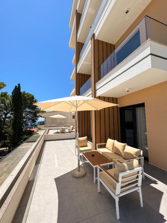 eine Terrasse mit Tisch, Stühlen und Sonnenschirm in der Unterkunft Square Residence & Pool in Ulcinj