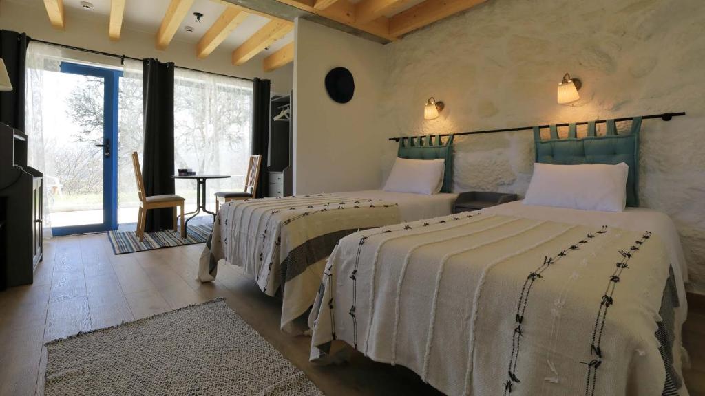 a bedroom with two beds and a table with a chair at Quinta Ecológica da Peneda Agroturismo by Peneda ecofarm in Arcos de Valdevez