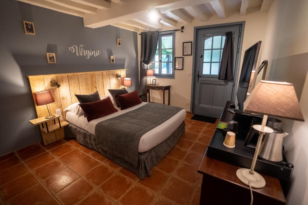 a bedroom with a bed and a table with a lamp at Domaine de Geffosse in Pont-lʼÉvêque