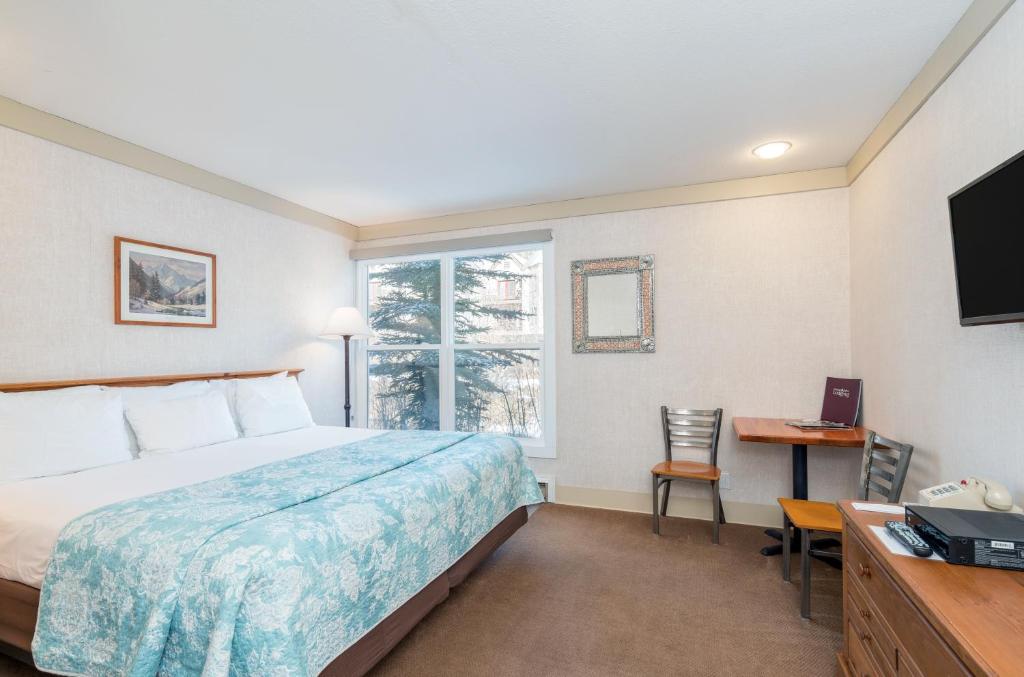 ein Hotelzimmer mit einem Bett, einem Schreibtisch und einem Fenster in der Unterkunft Mountainside Inn 211 Hotel Room in Telluride