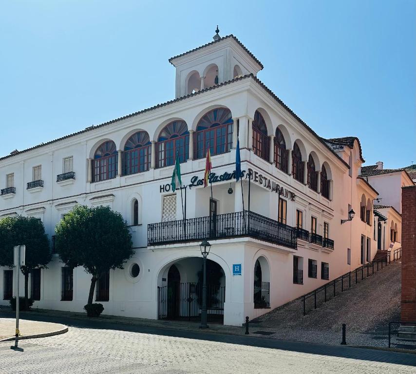un gran edificio blanco con balcón y 2 banderas en Hotel Los Castaños en Aracena
