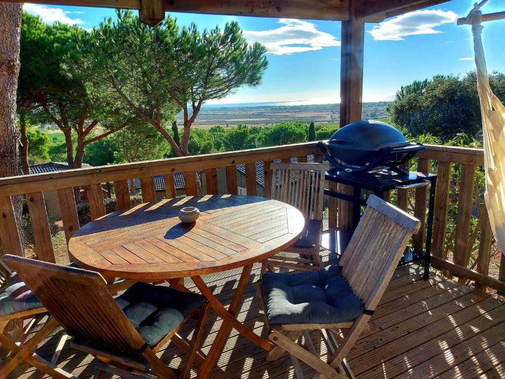 a wooden table and chairs on a deck with a grill at Cap d'Agde chalet vue sur la mer in Agde