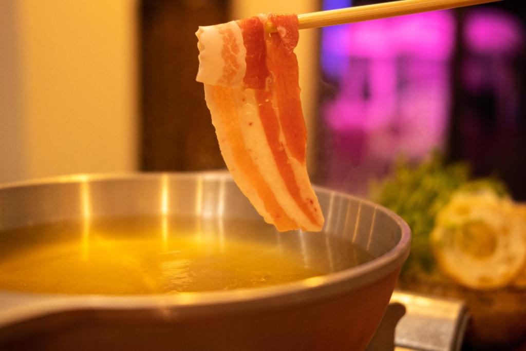 a piece of fruit is being dipped into a pot of soup at Kerama Blue Resort in Zamami