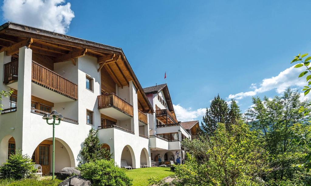 un grande edificio bianco con balconi e alberi di Aparthotel Muchetta a Davos