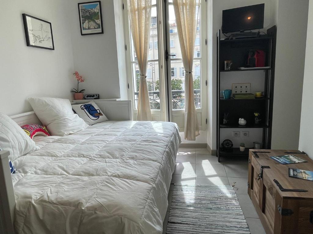 ein Schlafzimmer mit einem weißen Bett und einem Fenster in der Unterkunft La payotte du Vieux Port in Marseille