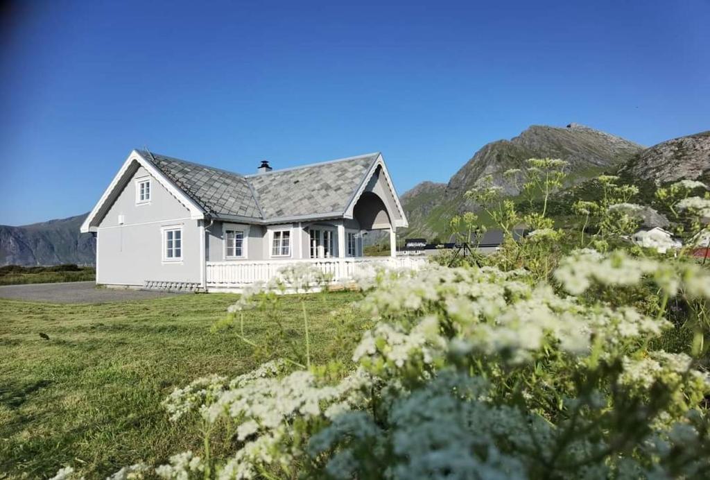 a white house with mountains in the background at BanPim Beachside Lofoten in Ramberg