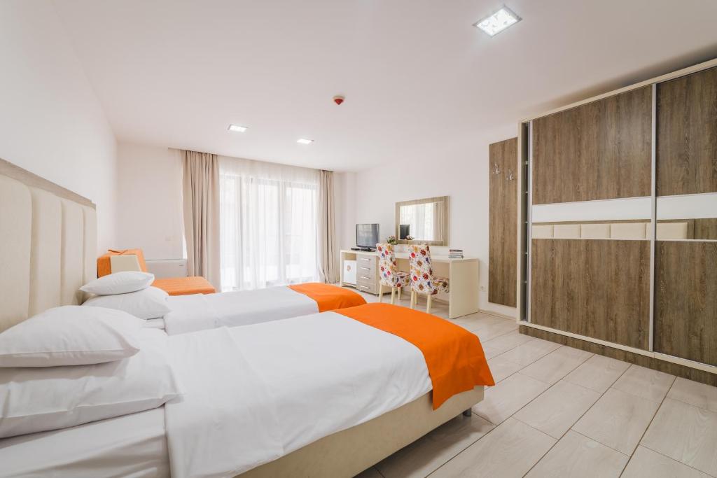 a bedroom with two beds with orange and white sheets at Hotel & Apartments HEC Residence in Sveti Stefan