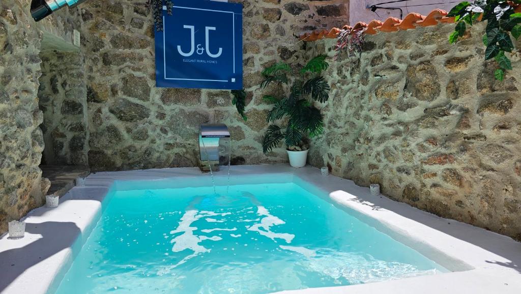 a swimming pool in a stone wall with a water fountain at El Edén Casas Rurales con Piscina y Jacuzzi in Montánchez