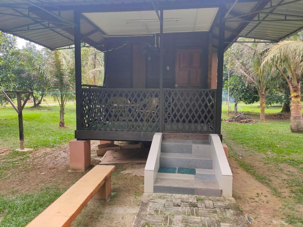 a gazebo with a bench in a park at NUR RAMADHAN CAMPSITE in Tanjung Malim