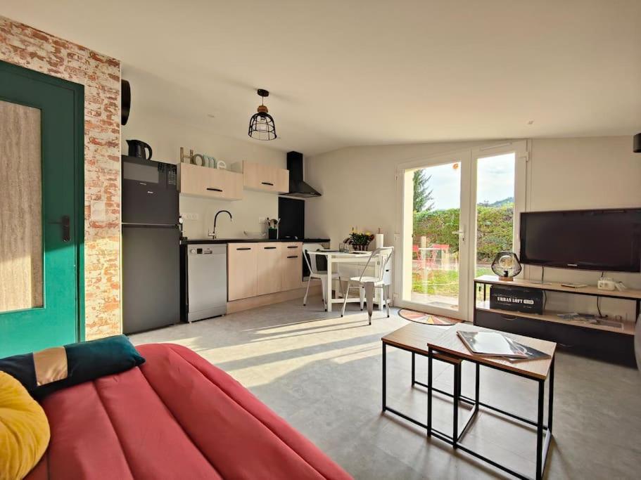 een woonkamer met een rode bank en een keuken bij Appartement moderne en rez de jardin - La Cascade 