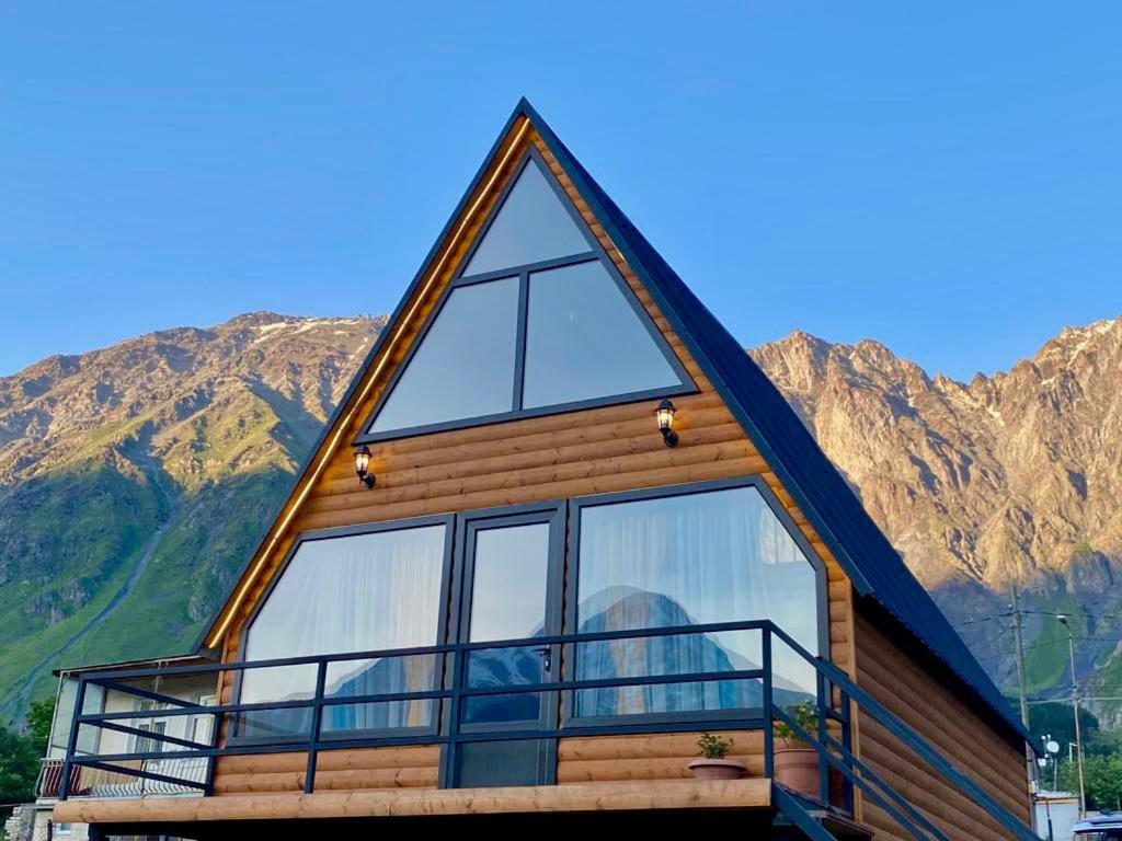 una baita di tronchi con montagne sullo sfondo di Qusha Cottage a Kazbegi