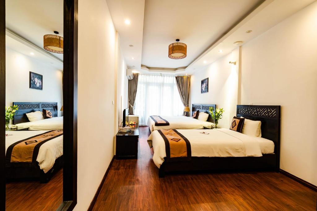 a hotel room with two beds and a mirror at Wild Lotus Hotel & Travel 2 in Hanoi