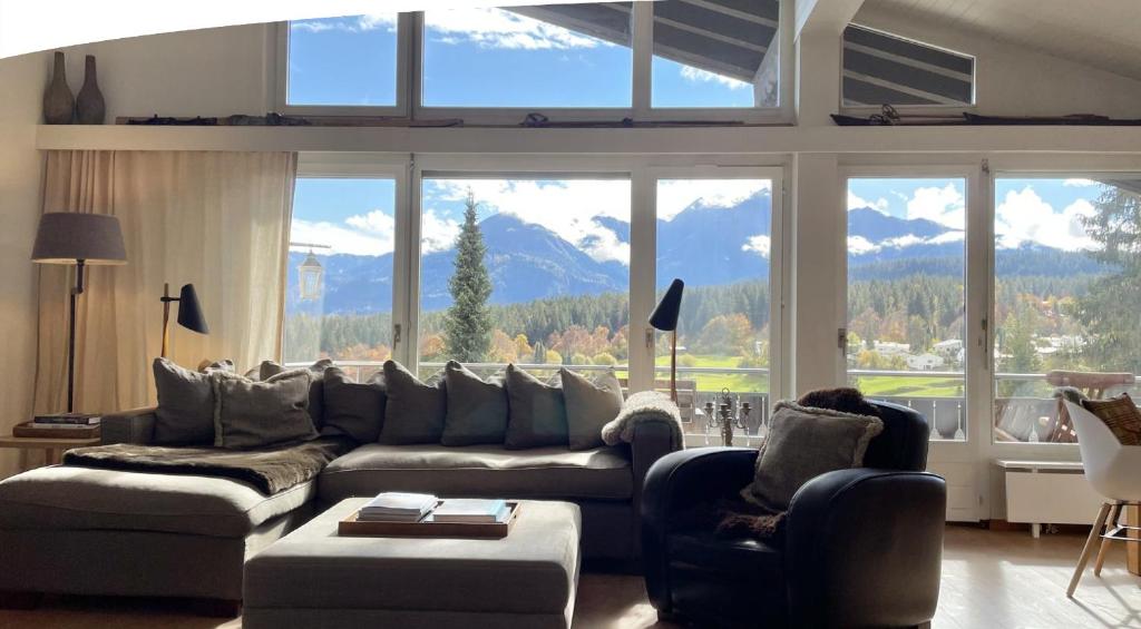 a living room with a couch and chairs and windows at Luxury Alpine Retreat with Wellness Area in Flims