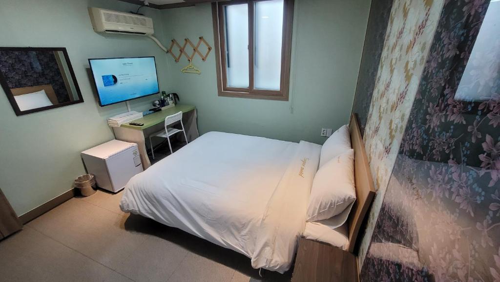 a bedroom with a bed and a desk with a computer at Sugar Motel in Gunsan
