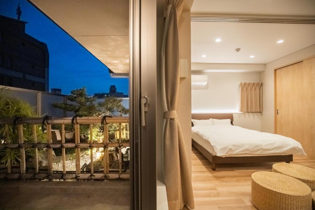 ein Schlafzimmer mit einem Bett und einem Balkon in der Unterkunft 有秋 双葉 in Osaka
