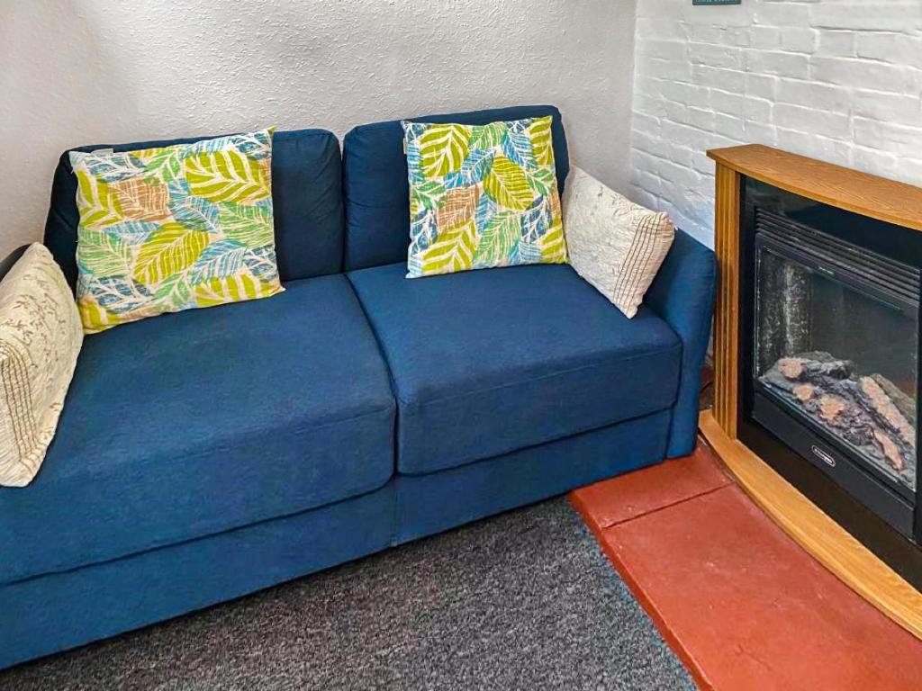 a blue couch with pillows next to a fireplace at The Hive - Uk44558 in Plaistow