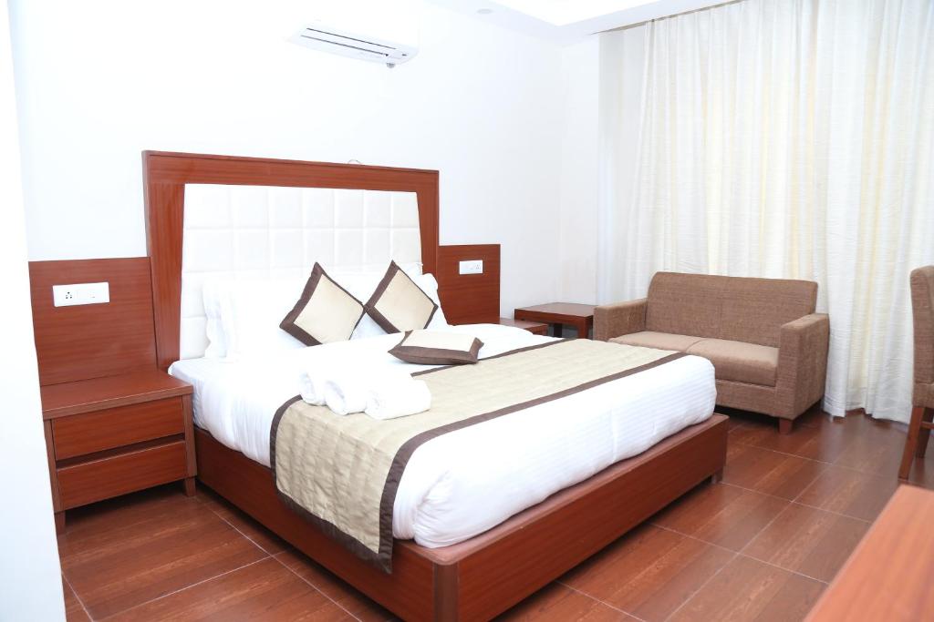 1 dormitorio con 1 cama grande y 1 silla en The Grand Kartikeye Hotel & Banquet Destination en Pālampur