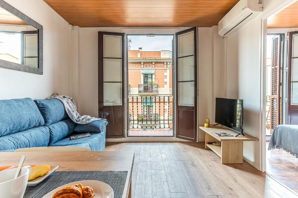 AB Nou de la Rambla في برشلونة: غرفة معيشة مع أريكة زرقاء وتلفزيون