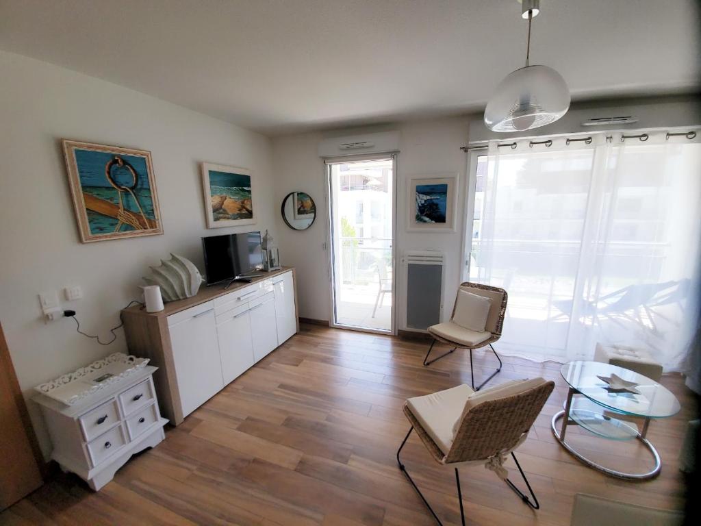 un salon avec une table, des chaises et une télévision dans l'établissement Le Carré des Sens, à La Rochelle