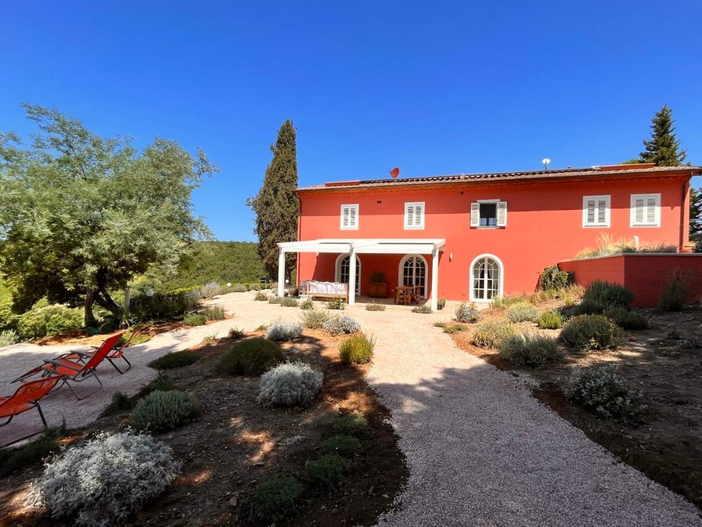 una casa roja con un jardín delante en Podere Terraviva, en Riparbella