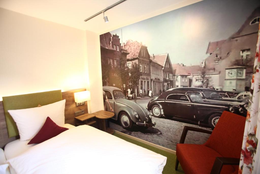 1 dormitorio con 1 cama y una pintura de coche en Hotel Schmidt am Markt, en Meppen