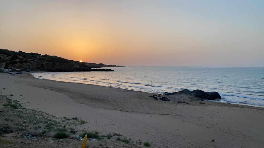einen Strand mit Sonnenuntergang am Meer in der Unterkunft La perla 