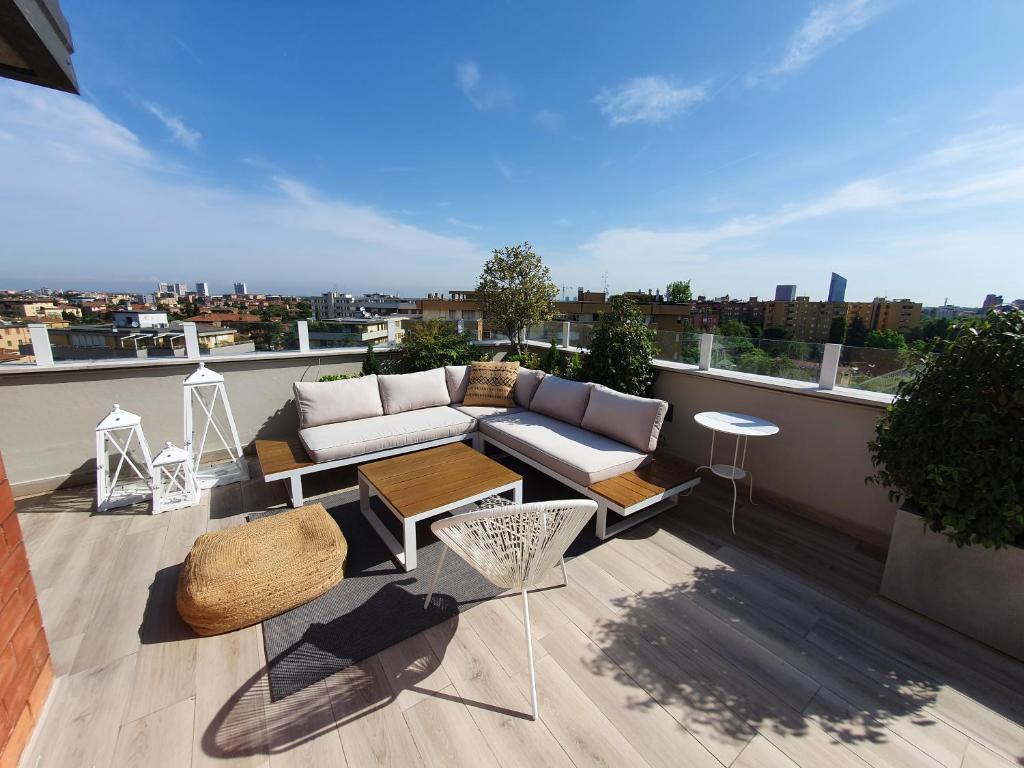 een balkon met een bank en tafels op een dak bij Penthouse F8 - Panoramic terrace, view Two Towers in Bologna