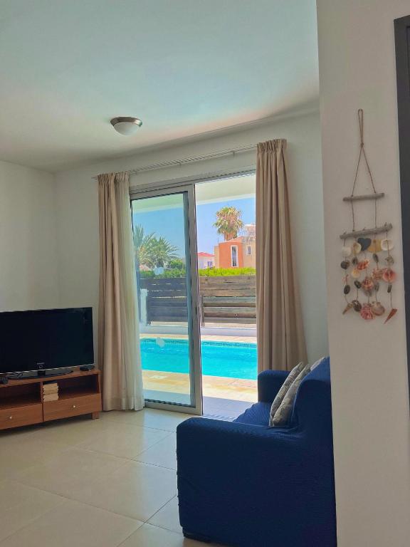 a living room with a blue couch and a tv at 3 Bedroom Coral Bay Beach Seaview Villa I Private Pool in Peyia