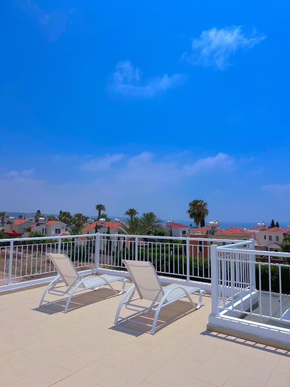 two chairs sitting on a deck with a railing at 3 Bedroom Coral Bay Beach Seaview Villa I Private Pool in Peyia