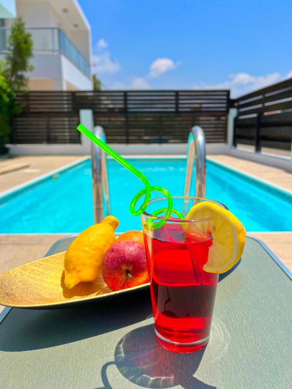 a drink on a table next to a plate of fruit at 3 Bedroom Coral Bay Beach Seaview Villa I Private Pool in Peyia