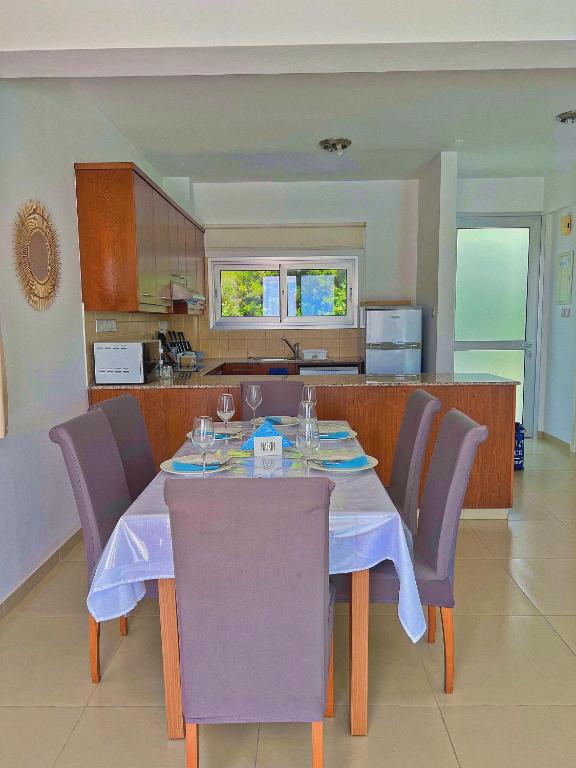a dining room table with purple chairs and a kitchen at 3 Bedroom Coral Bay Beach Seaview Villa I Private Pool in Peyia