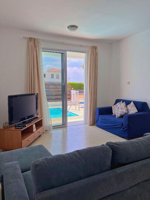 a living room with a couch and a flat screen tv at 3 Bedroom Coral Bay Beach Seaview Villa I Private Pool in Peyia