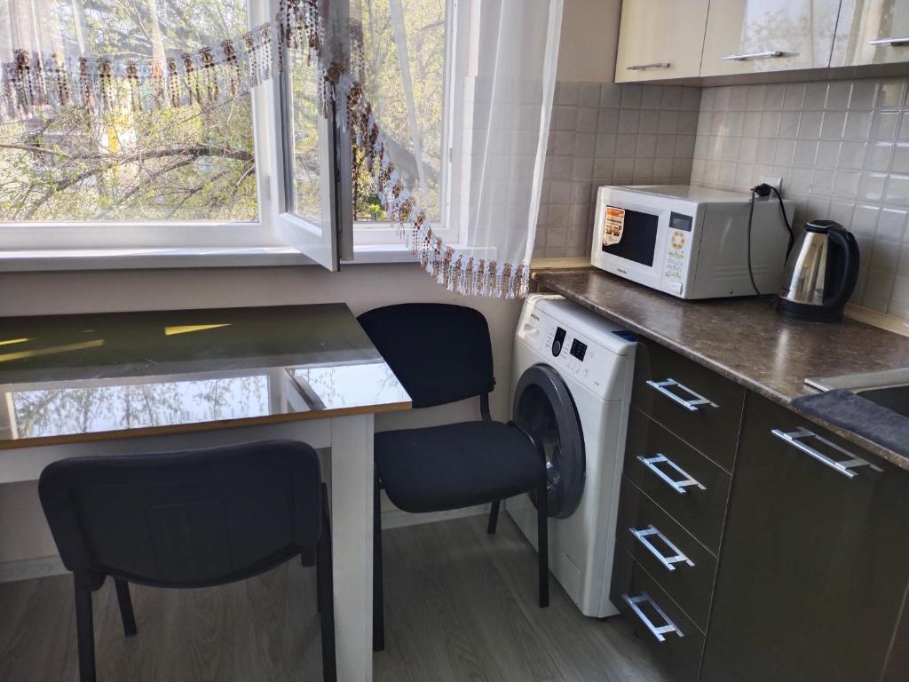 a kitchen with a washing machine and two chairs at Амид 3 in Khujand