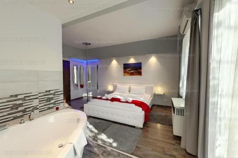 a bedroom with a white bed and a bath tub at Velnök Luxus Apartman in Makó