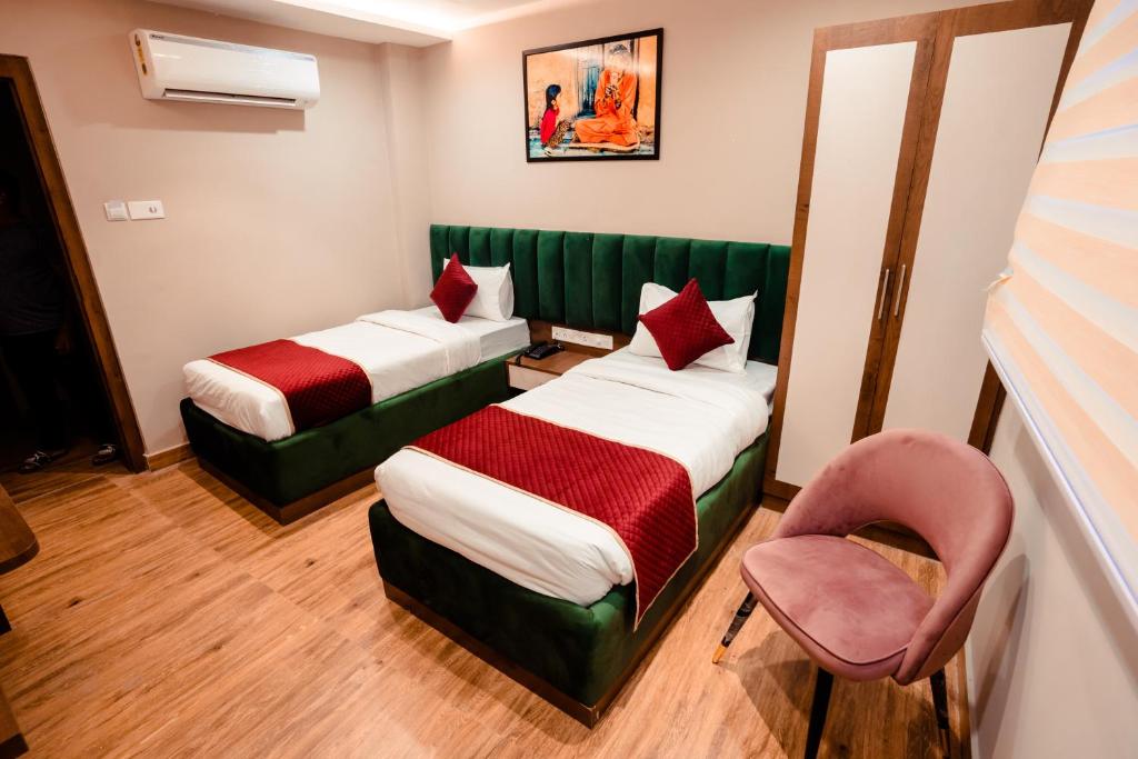 a hotel room with two beds and a chair at HOTEL JSR GANGA in Varanasi