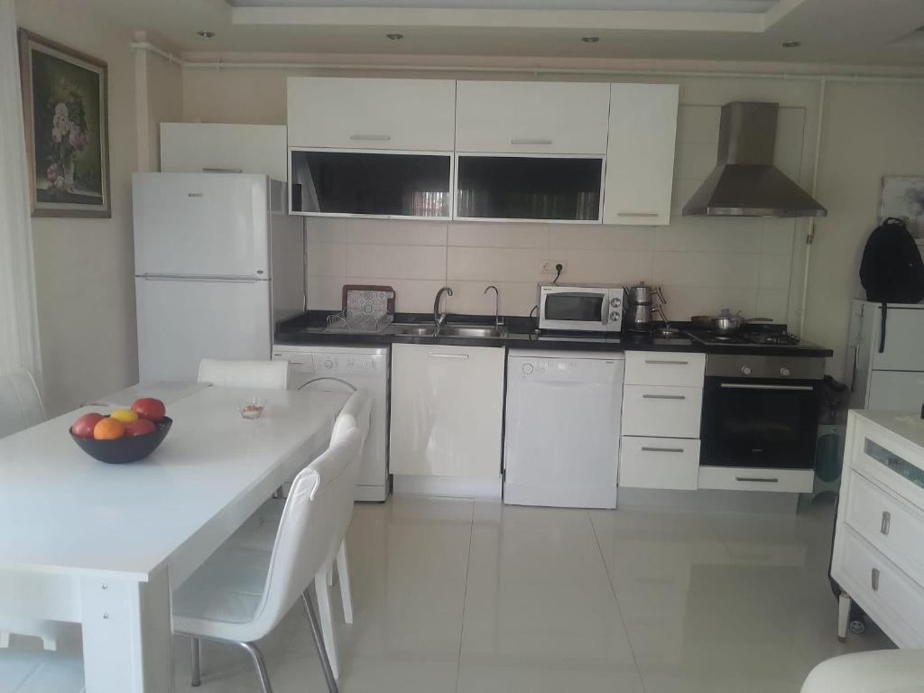 a kitchen with white appliances and a table with a bowl of fruit on it at Konyaaltı Denize Yakın Kiralık Daire in Antalya
