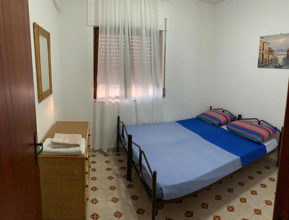 una camera con un letto blu e una finestra di Casa vacanza, 200 m dal mare a Scalea