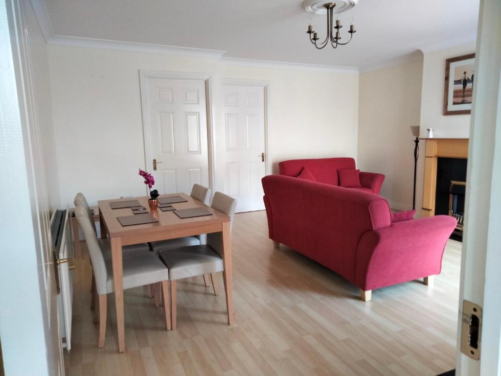 a living room with a table and a red couch at Community Courtyard Bungalow Apt in Drogheda